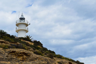 Low angle view of lighthouse by building against sky