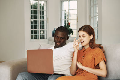 Couple using laptop while sitting at home