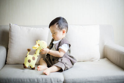 Portrait of cute boy playing with teddy bear at home