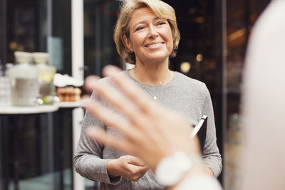 Happy businesswoman looking at female colleague outside restaurant
