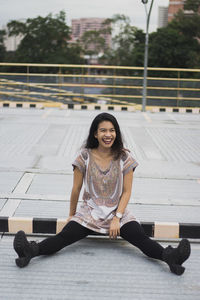 Portrait of smiling young woman sitting outdoors