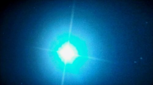 Close-up of illuminated light over blue background