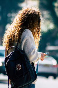 Midsection of woman holding smart phone while standing outdoors