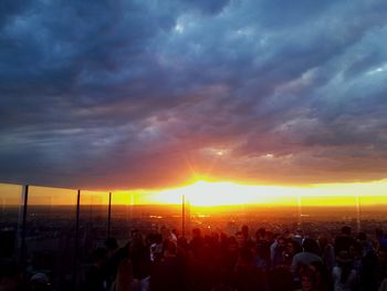 Crowd at sunset against sky