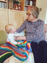 Grandmother playing with grandson on sofa at home