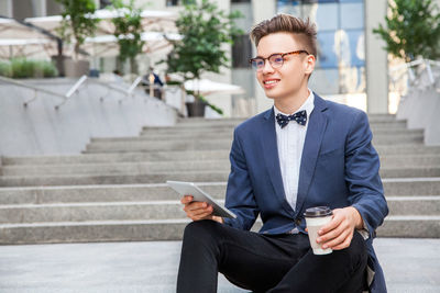 Young man using mobile phone while sitting outdoors