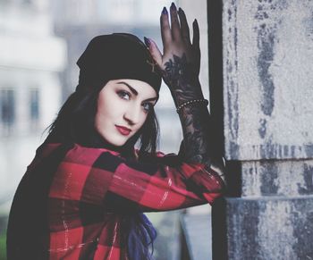 Portrait of beautiful young woman standing against wall