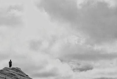 Low angle view of man standing on mountain against sky