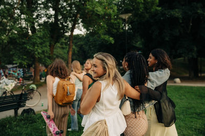 Smiling blond teenage girl walking with female friends at park