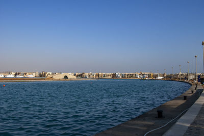 Scenic view of sea by buildings against clear blue sky