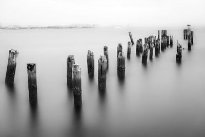 Wooden posts on sea against sky