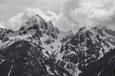 Scenic view of snow covered mountains against cloudy sky