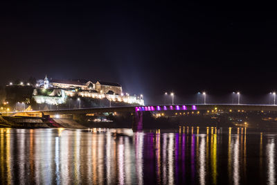 Illuminated bridge over river against sky at night