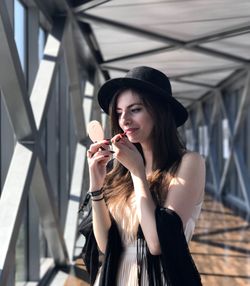 Young woman applying lipstick at covered walkway