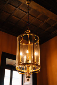 Low angle view of illuminated light bulb hanging from ceiling