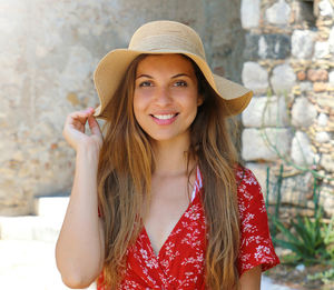 Close up portrait of smiling beautiful woman with red dress and hat outdoors.