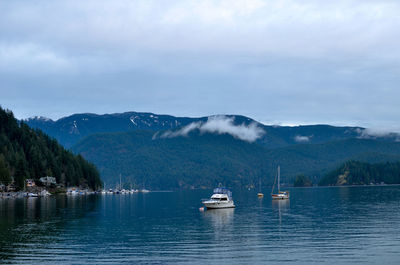 Sailboats in sea against mountains