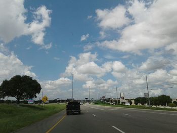 Cars on road against cloudy sky