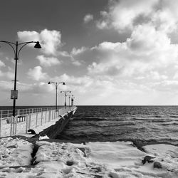 Street light by sea against sky