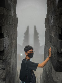 Full length of man standing by wall of building