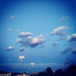 Low angle view of illuminated street light against blue sky