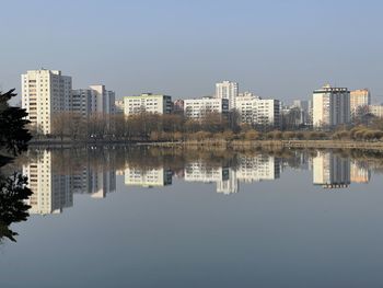 Reflection of buildings in lake against clear sky