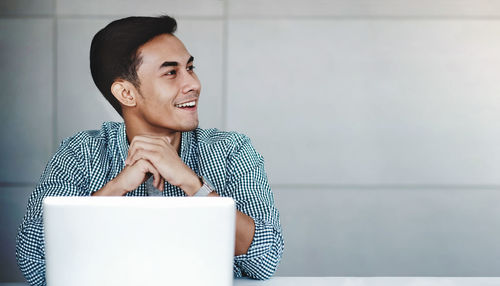 Young man looking away while sitting on table