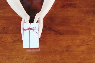 Cropped hand holding gift box on table