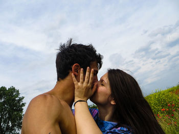 Close-up of couple kissing against cloudy sky