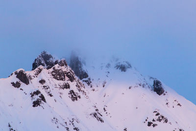 Low angle view of snowcapped mountains against clear blue sky