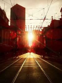 Road passing through city at sunset