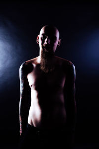 Portrait of shirtless man against black background