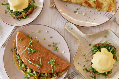 Eggs benedict with sauce, sourdough bread, tofu, young onion, greens. pancakes filled with mushrooms