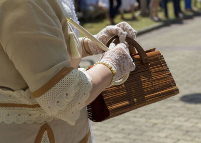 Midsection of woman holding purse on street