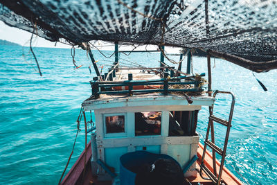 Fishing boat sailing in sea against blue sky