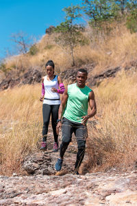 Full length of couple running on mountain during sunny day