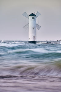 Lighthouse by sea against sky