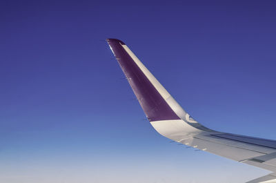 Low angle view of airplane flying against clear blue sky