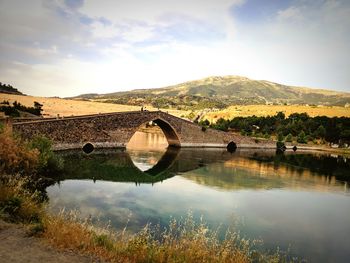 Arch bridge over lake against sky