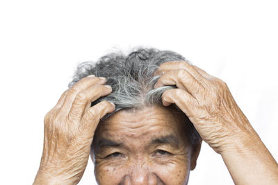 Cropped image of senior woman scratching head against white background