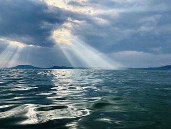 Scenic view of lake against sky sunlight through cloud