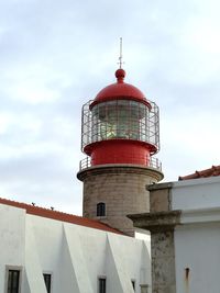 Low angle view of lighthouse by building against sky