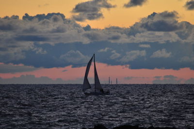 Silhouette boat sailing in sea against sky during sunset