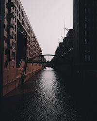 Bridge over river amidst buildings against sky in city