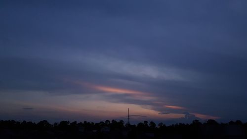 Low angle view of silhouette trees against dramatic sky