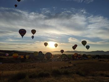 Hot air balloons on field against sky during sunset