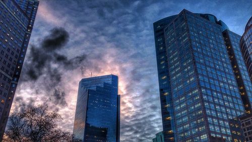 Low angle view of modern building against cloudy sky