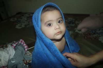 Cute baby girl wrapped in towel on bed at home