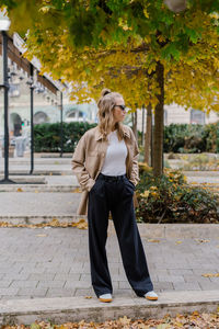 Portrait of young woman standing on footpath