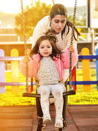 Portrait of girl sitting on swing in park